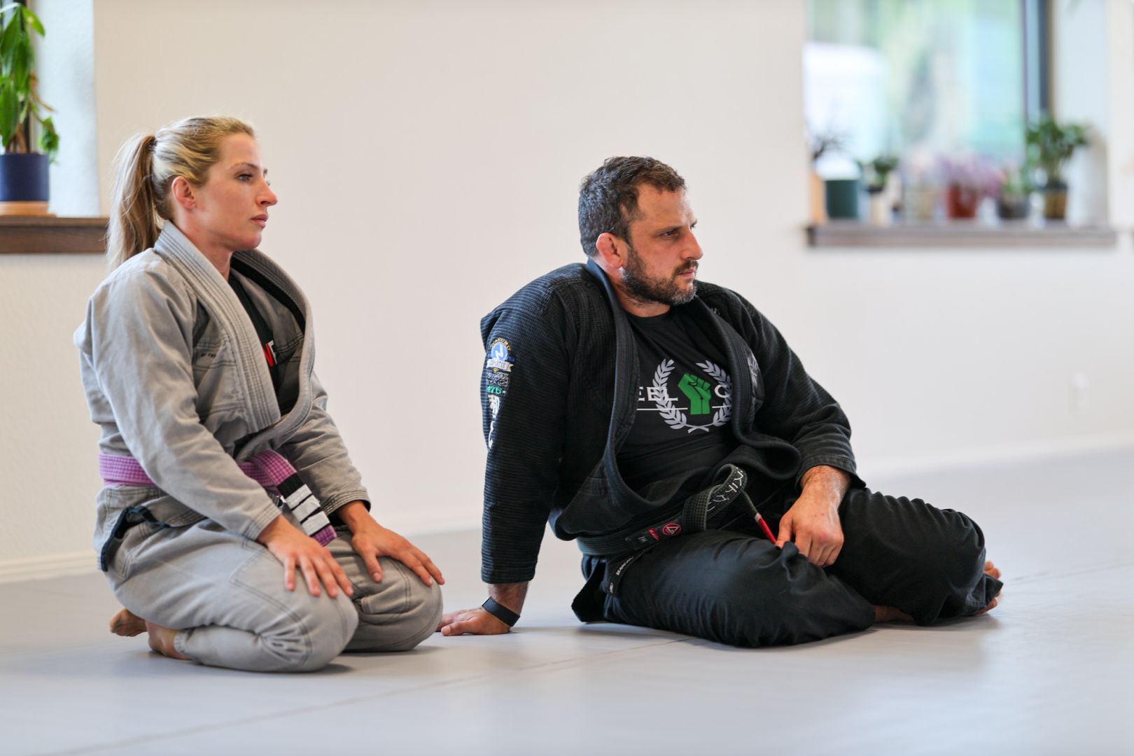 Two members sitting and listening on the mats at Golden Jiu Jitsu